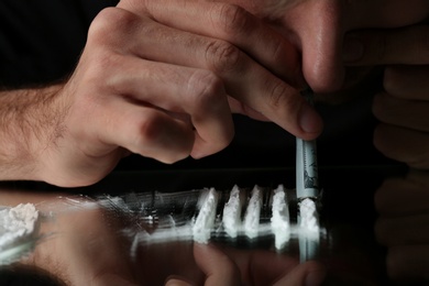 Photo of Drug addict taking cocaine at table, closeup view