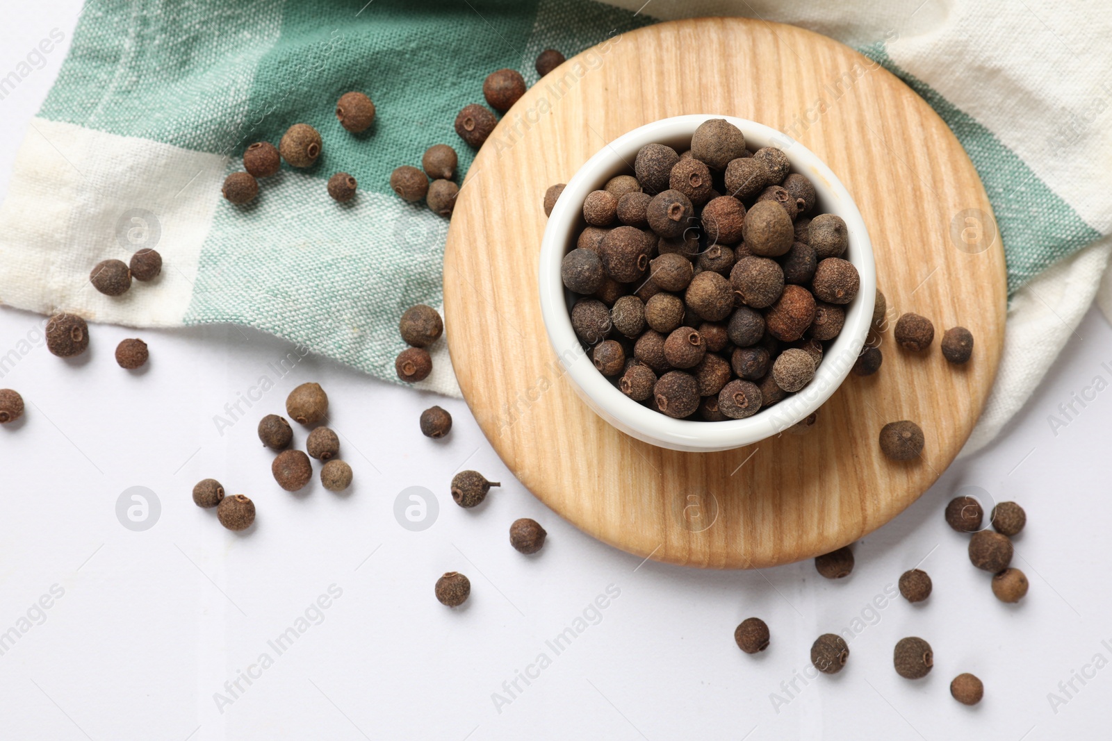 Photo of Dry allspice berries (Jamaica pepper) on white tiled table, top view