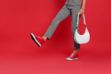 Woman with stylish bag on red background, closeup