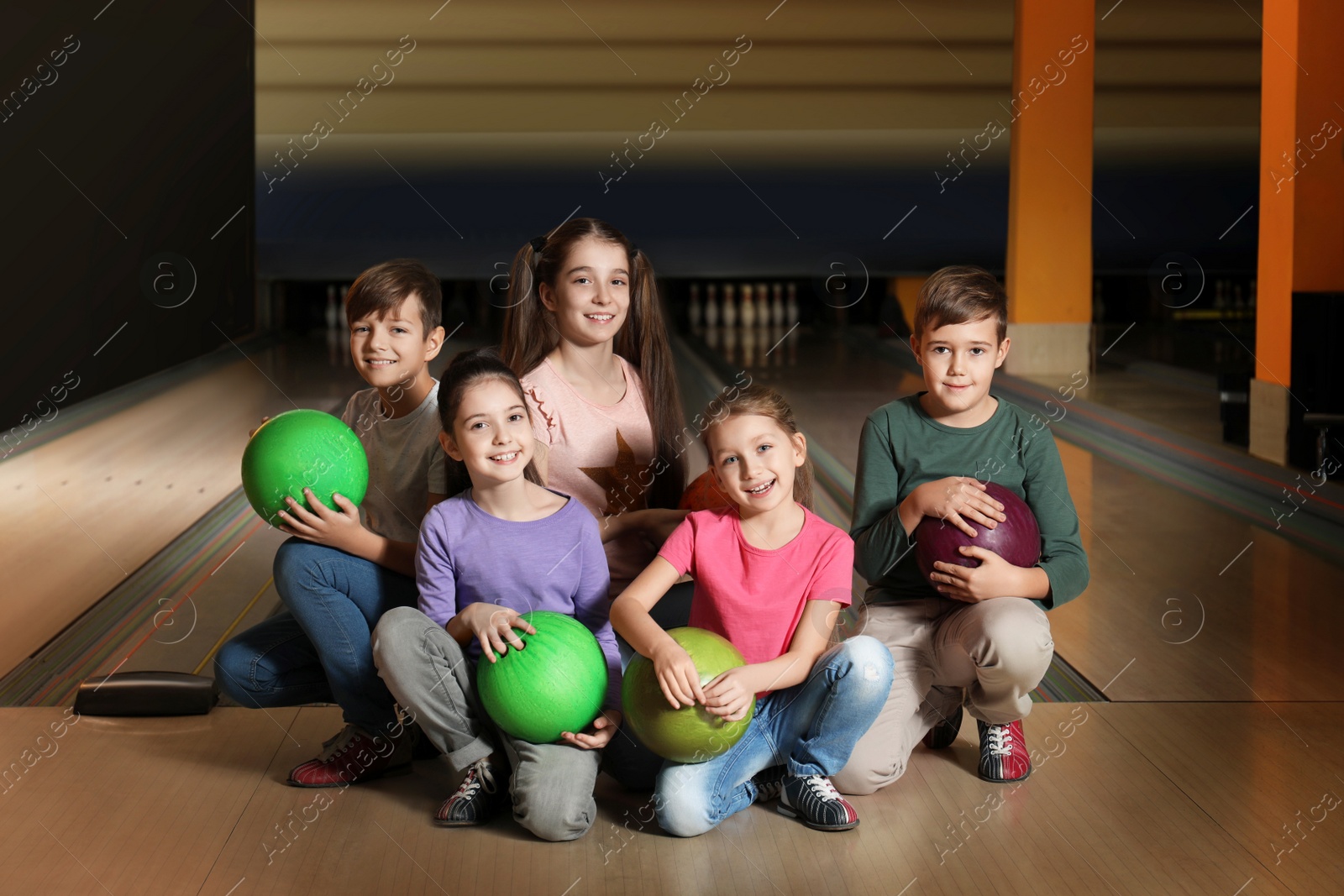 Photo of Happy children with balls in bowling club