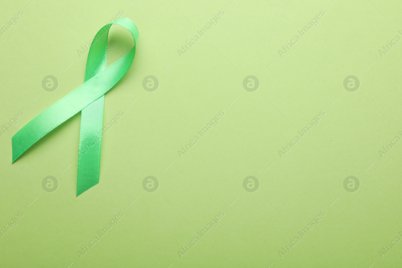 Photo of World Mental Health Day. Green ribbon on color background, top view with space for text