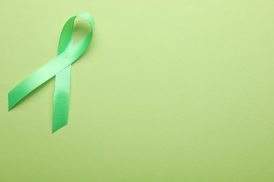 World Mental Health Day. Green ribbon on color background, top view with space for text