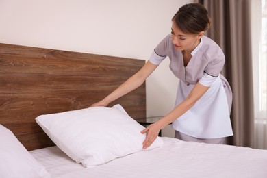 Photo of Beautiful chambermaid making bed in hotel room