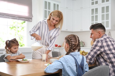 Photo of Happy family having breakfast together at table in modern kitchen