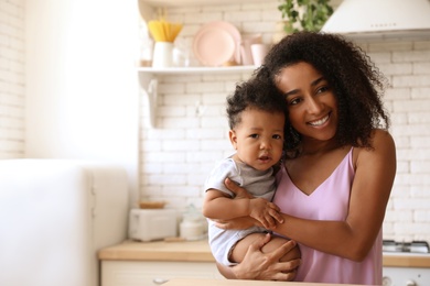 African-American woman with her baby in kitchen. Happiness of motherhood