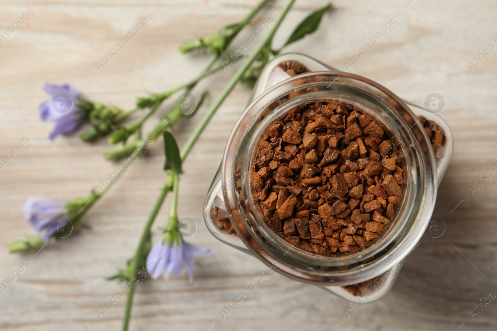 Photo of Jar of chicory granules on white wooden table, top view. Space for text