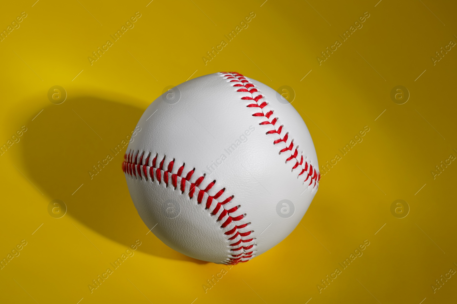 Photo of One baseball ball on yellow background, top view