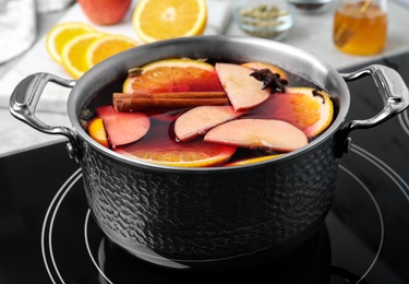 Photo of Delicious hot mulled wine in pot on stove, closeup
