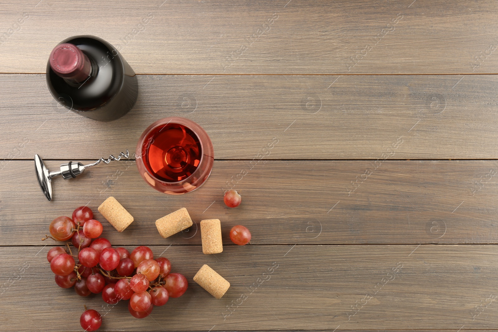 Photo of Wine, corks, grapes and corkscrew on wooden table, flat lay. Space for text