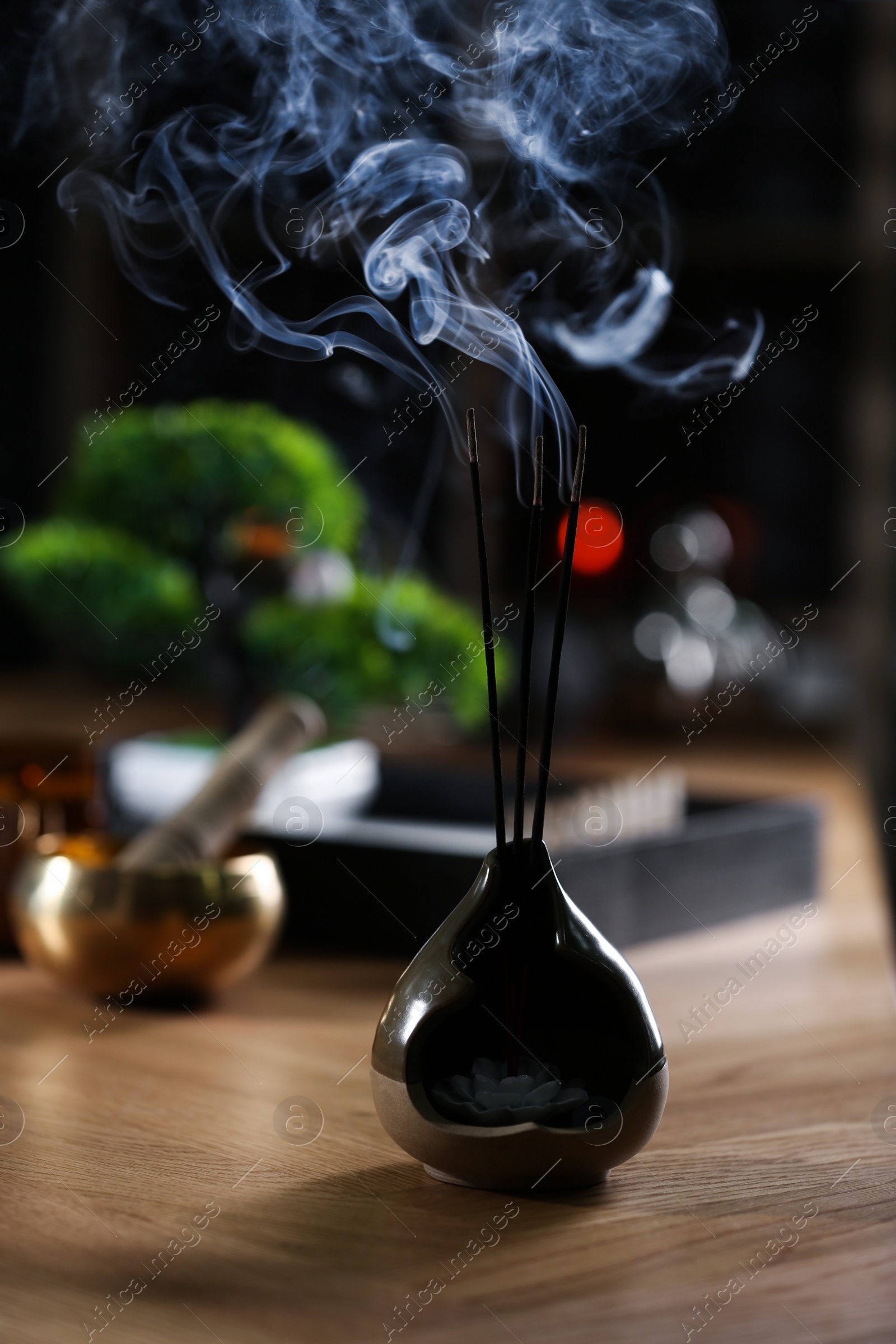 Photo of Incense sticks smoldering on wooden table indoors