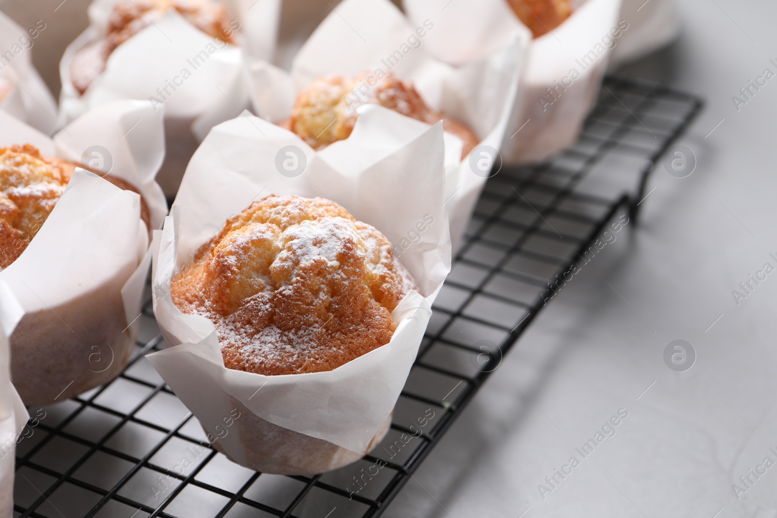 Photo of Delicious muffins with powdered sugar on light table, closeup