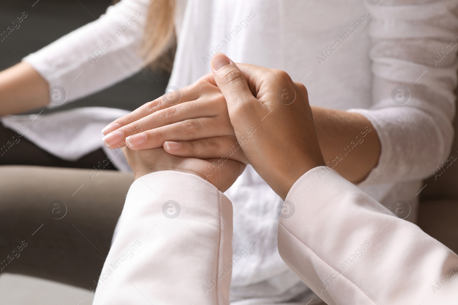 Photo of Women holding hands indoors, closeup. Concept of support and help