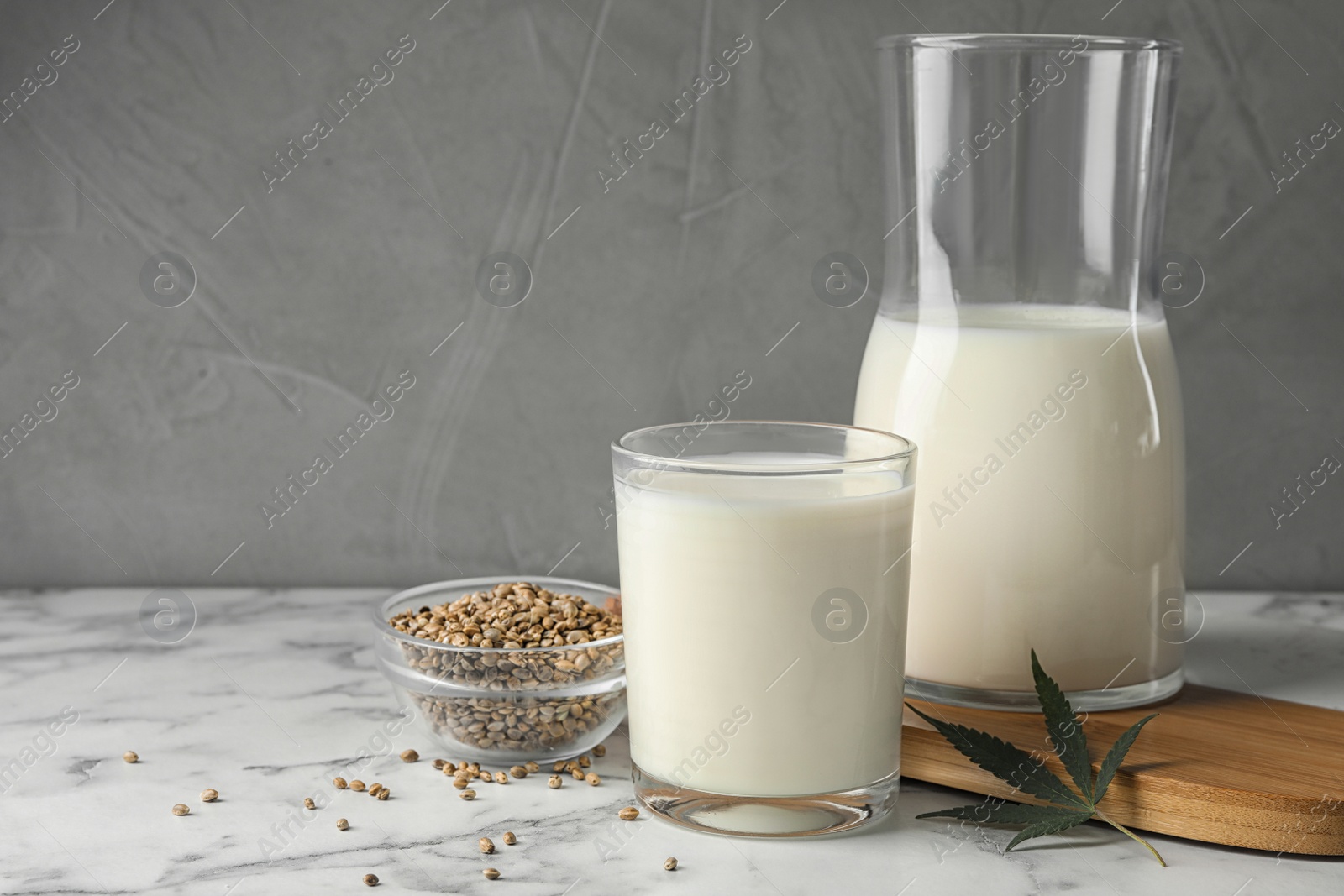 Photo of Composition with glassware of hemp milk on marble table against grey background. Space for text