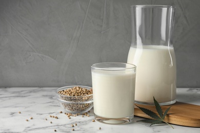 Composition with glassware of hemp milk on marble table against grey background. Space for text