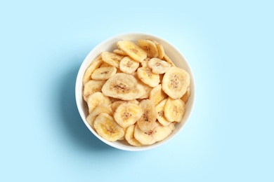 Photo of Bowl with banana slices on color background, top view. Dried fruit as healthy snack