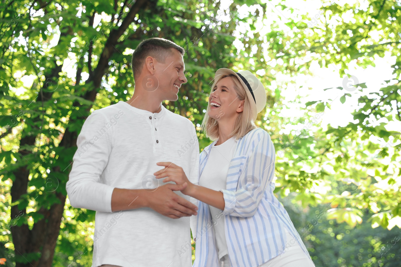 Photo of Happy couple walking along park on summer day