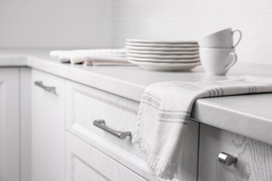 Photo of Soft kitchen towel and dishware on countertop indoors, space for text