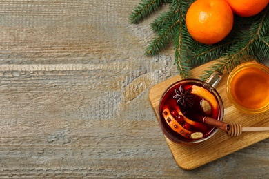 Glass cup of tasty mulled wine on wooden background, flat lay. Space for text