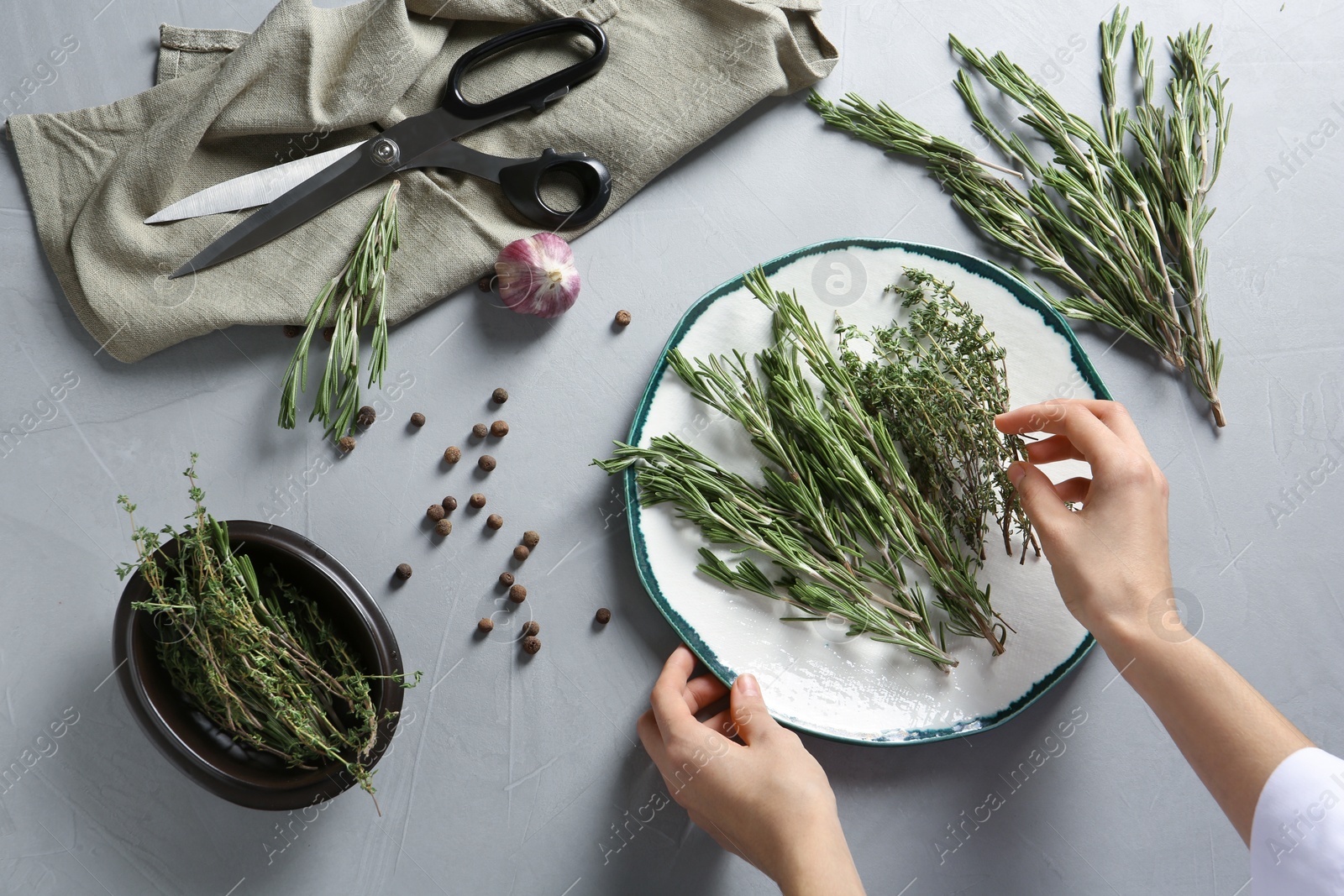 Photo of Woman with rosemary and other aromatic herbs at table, top view