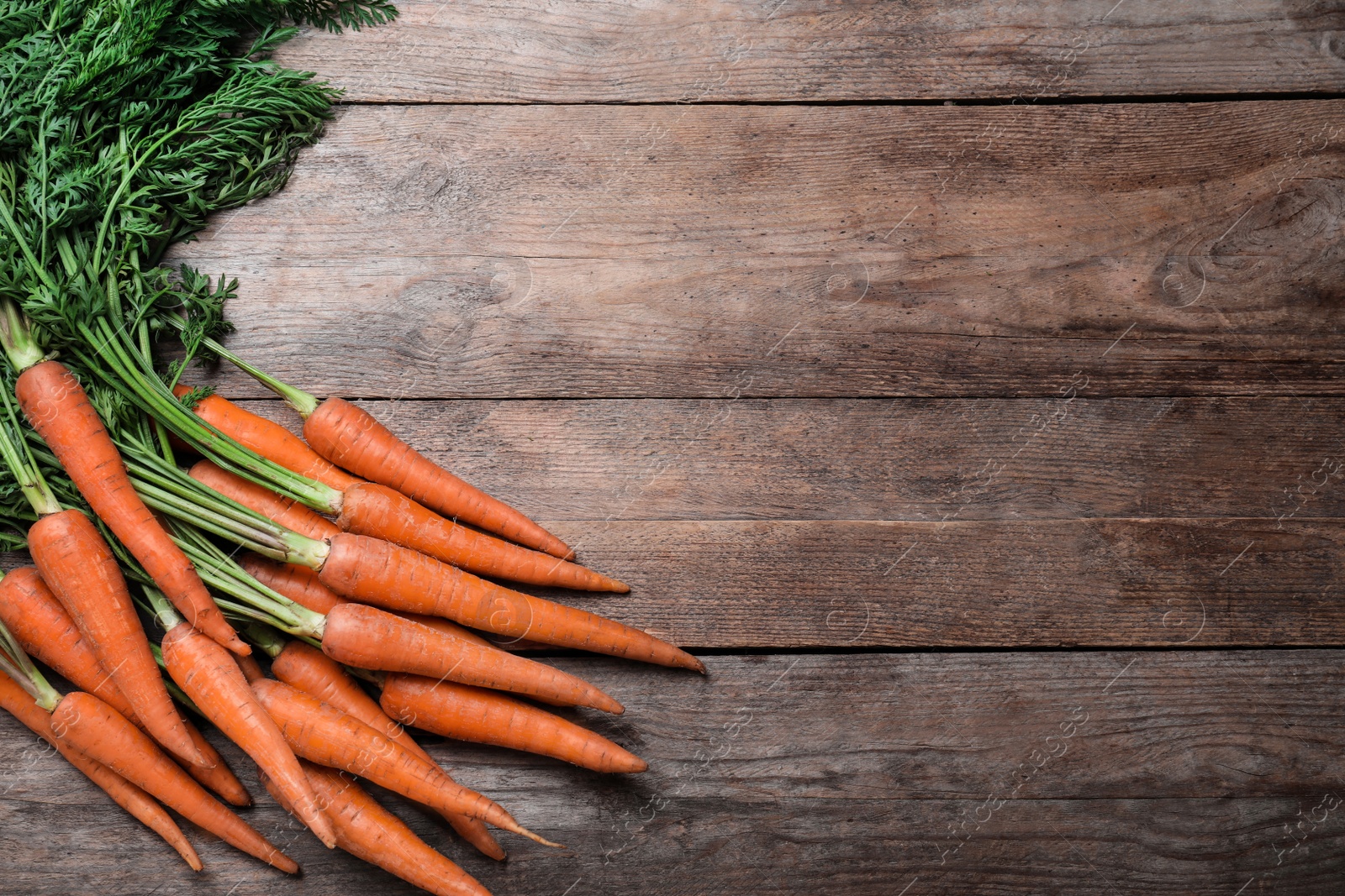 Photo of Ripe carrots on wooden table, flat lay. Space for text