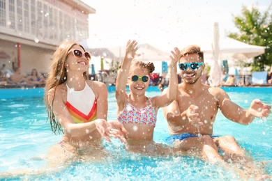 Photo of Happy family having fun in pool on sunny day