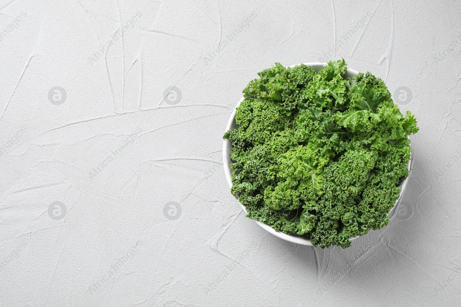 Photo of Fresh kale leaves on white table, top view. Space for text