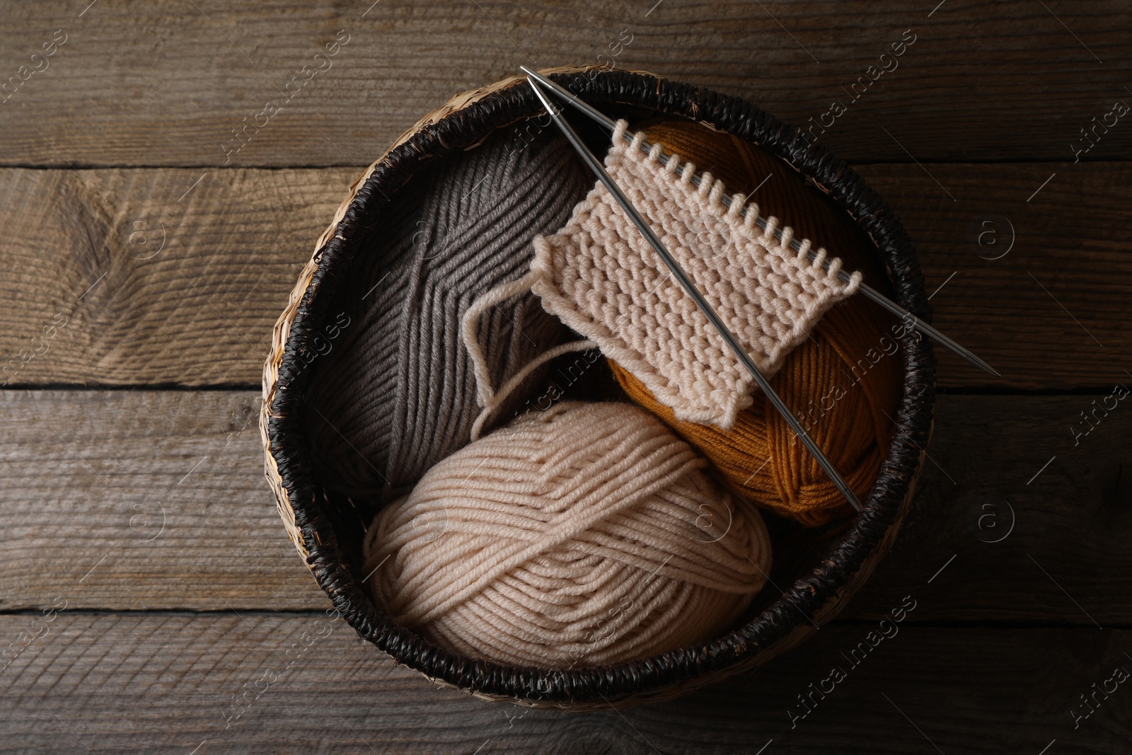 Photo of Soft colorful yarns, knitting and metal needles on wooden table, top view