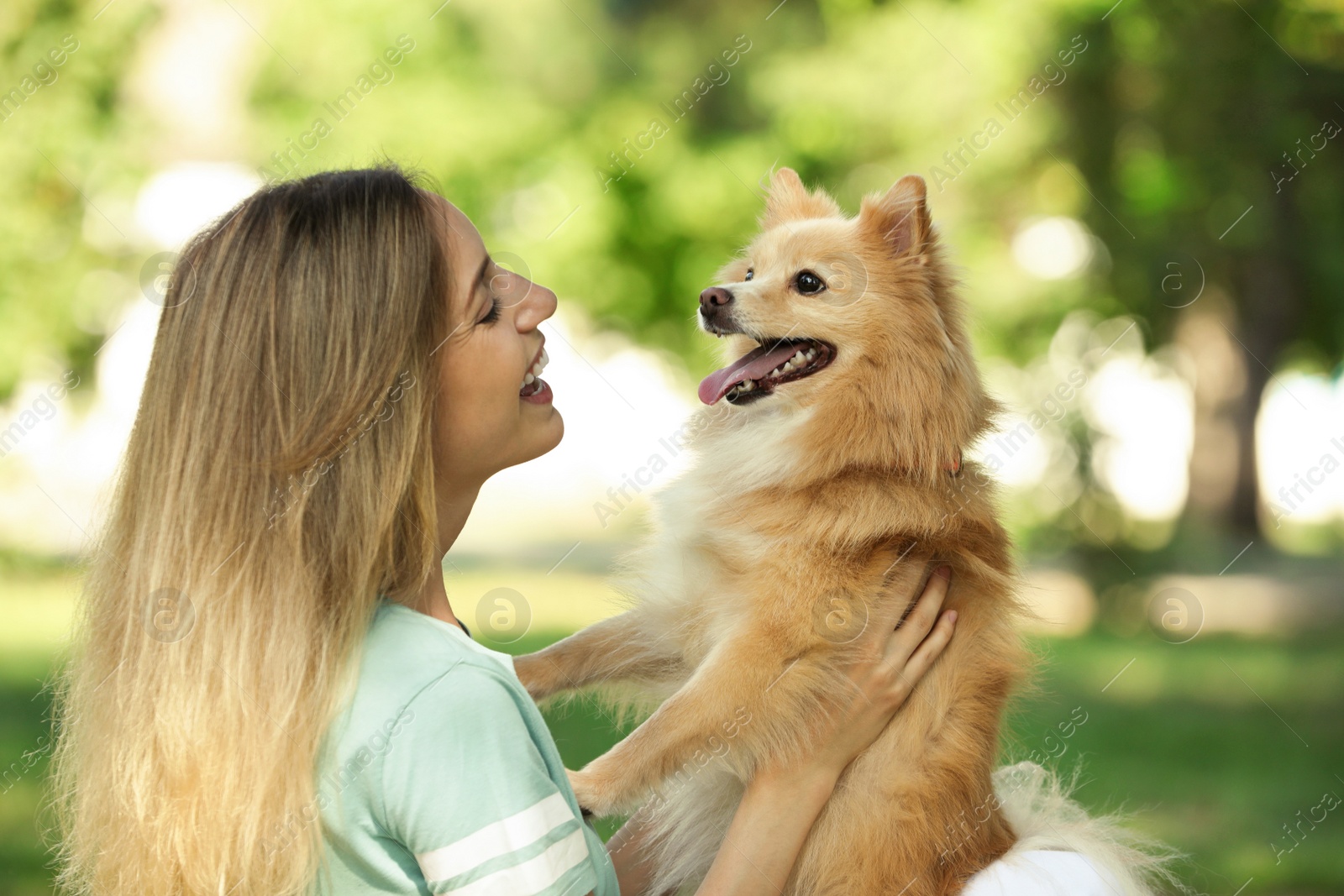 Photo of Young woman with her cute dog in park on sunny day