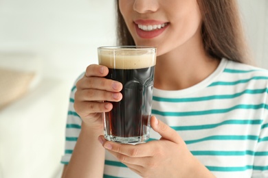 Young woman with cold kvass indoors, closeup. Traditional Russian summer drink