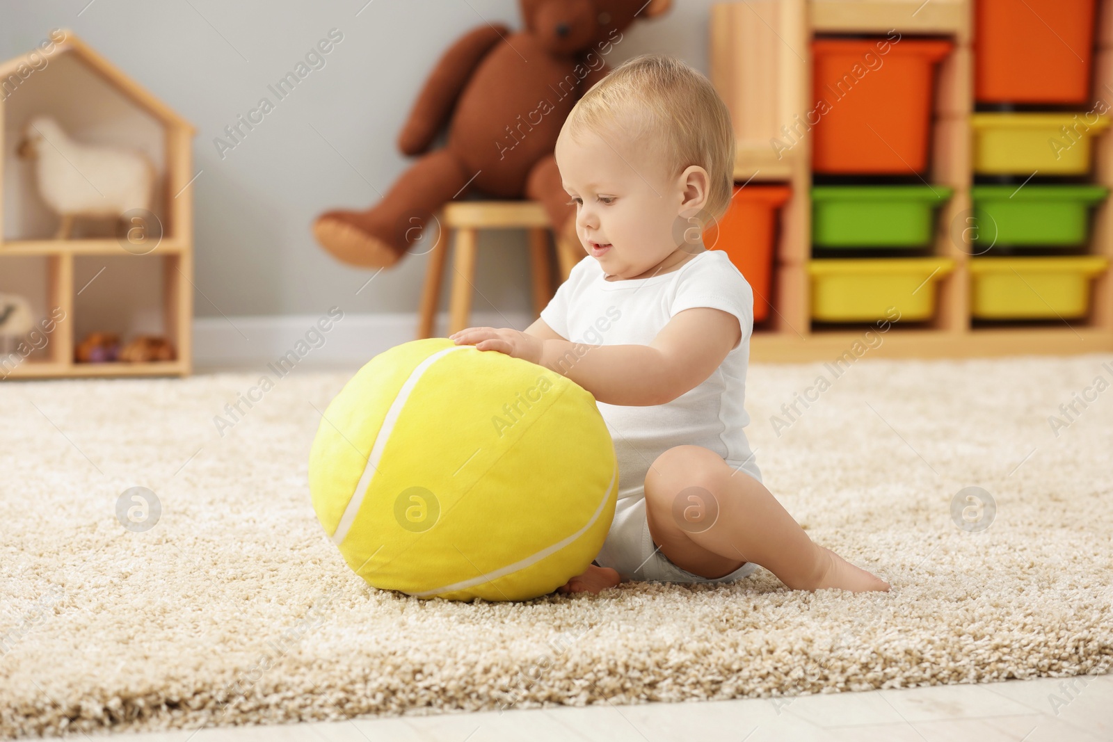 Photo of Children toys. Cute little boy playing with soft toy ball on rug at home