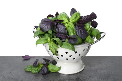 Photo of Colander with fresh basil leaves on grey table against white background