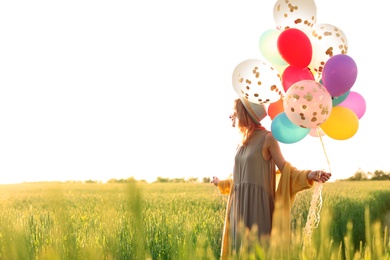 Young woman with colorful balloons outdoors on sunny day