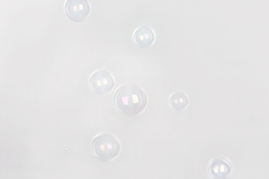 Beautiful translucent soap bubbles on light background