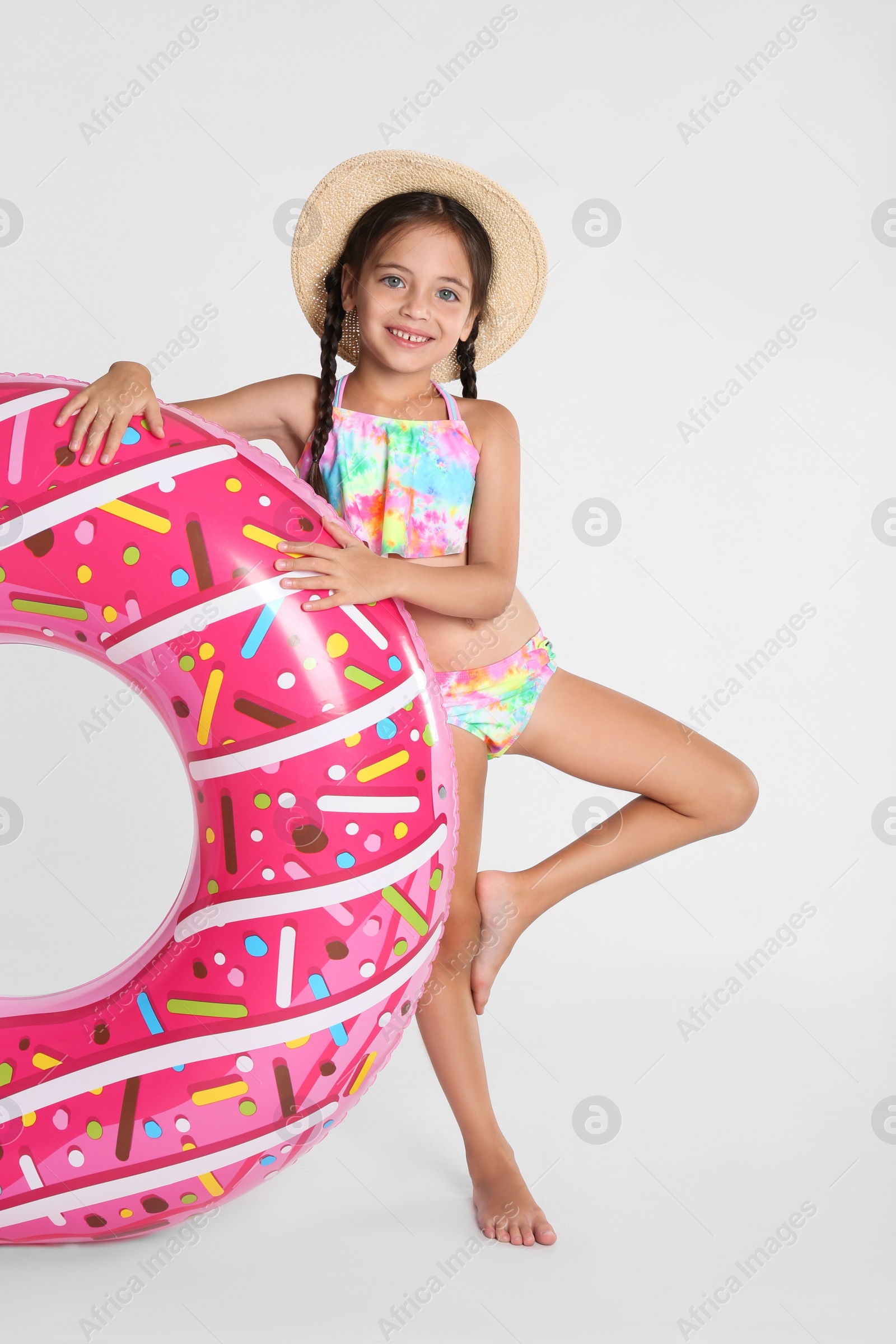 Photo of Cute little child in beachwear with bright inflatable ring on white background