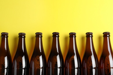 Bottles of beer on yellow background, flat lay. Space for text