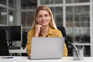 Woman working on laptop at white desk in office