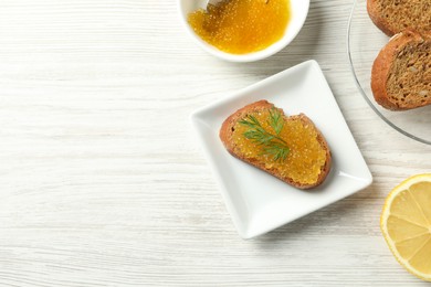 Photo of Slice of bread with pike caviar on white wooden table, flat lay