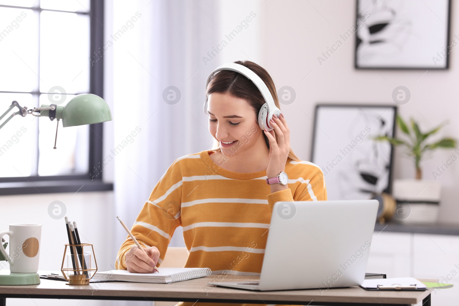 Photo of Teenage girl listening to music while doing homework in her room