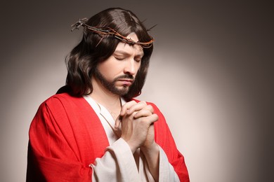 Jesus Christ with crown of thorns praying on beige background, space for text
