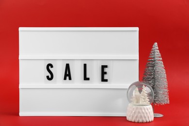 Lightbox with word Sale and Christmas decor on red background