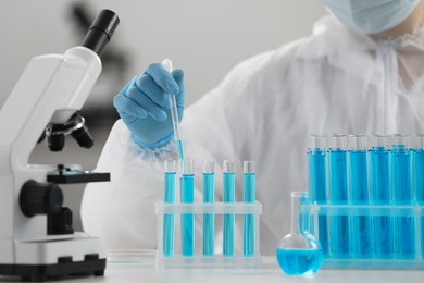 Photo of Scientist dripping sample into test tube in laboratory, closeup