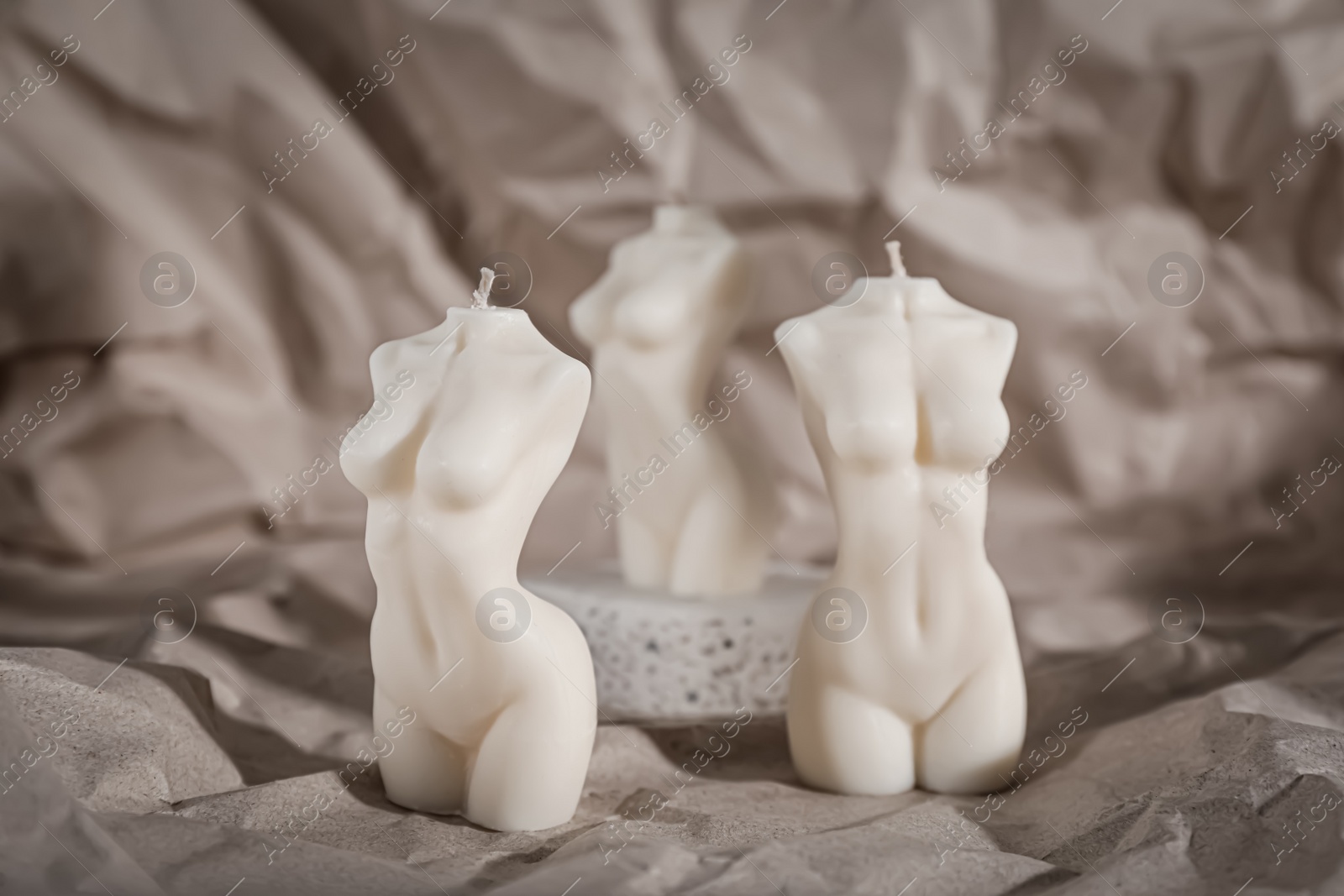 Photo of Beautiful female body shaped candles on crumpled paper