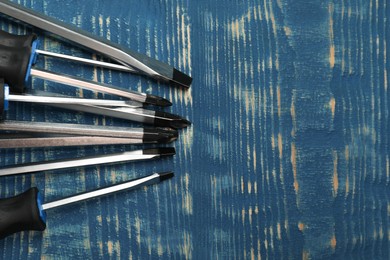 Set of screwdrivers on blue wooden table, flat lay. Space for text