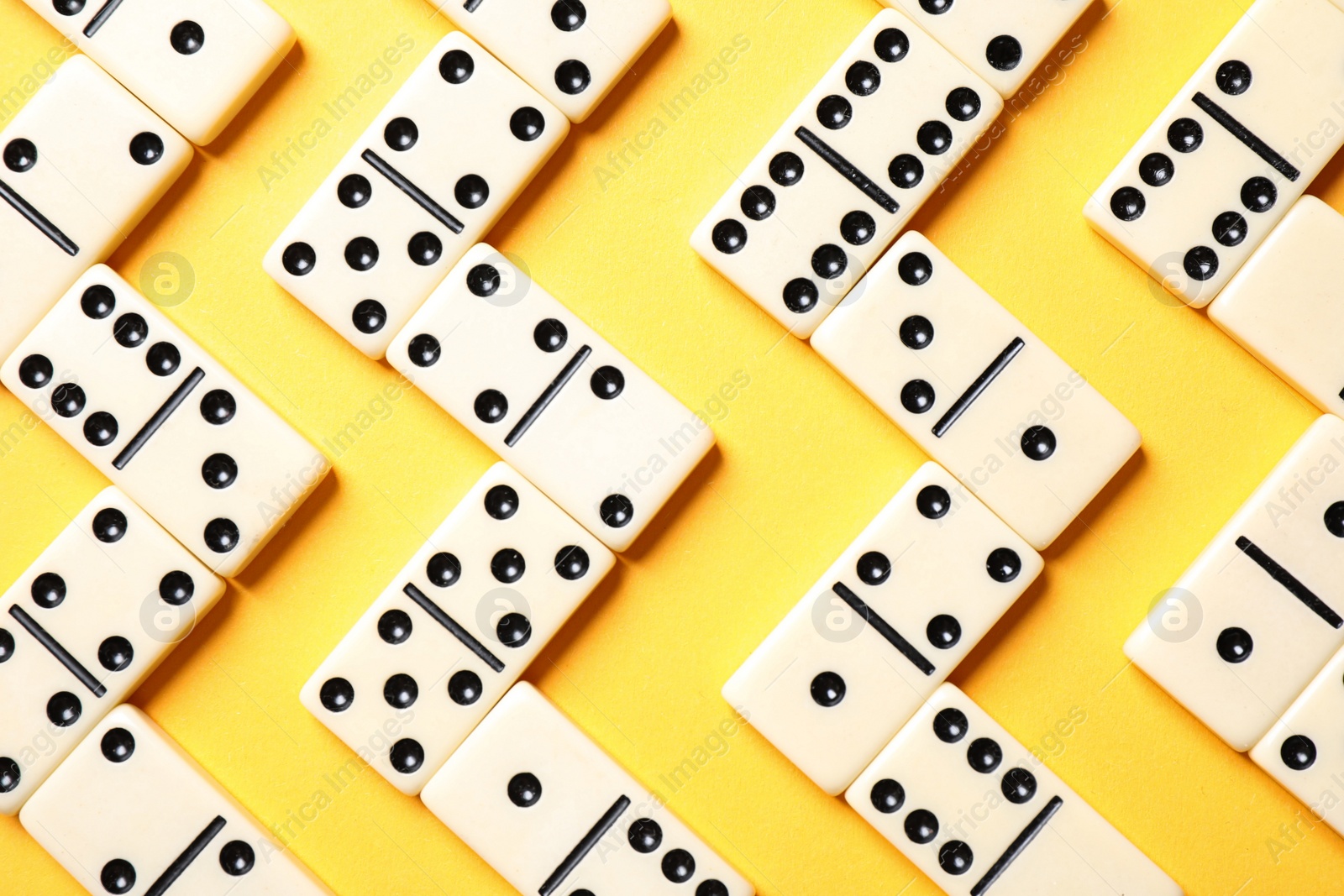 Photo of Classic domino tiles on yellow background, flat lay