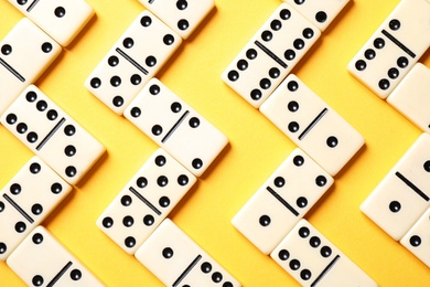 Classic domino tiles on yellow background, flat lay