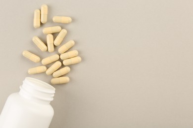 Bottle and vitamin capsules on light background, top view. Space for text