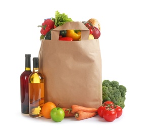 Photo of Paper bag with different groceries on white background