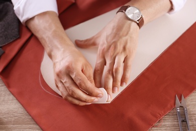 Tailor working with cloth at table in atelier