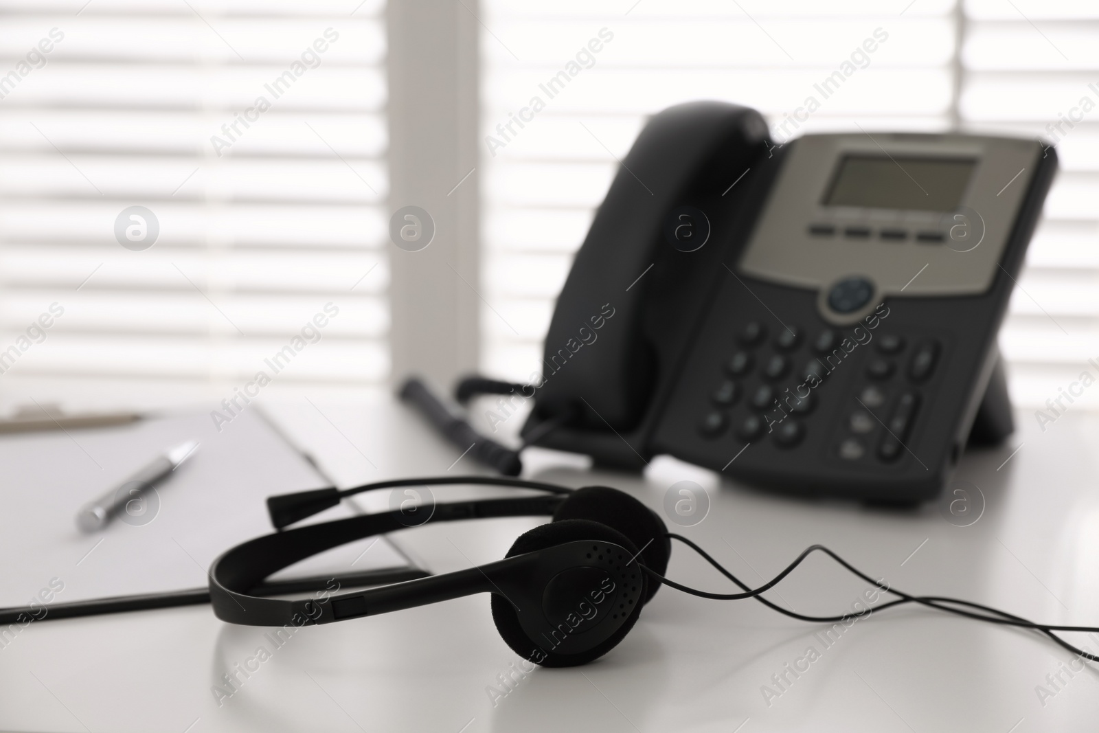 Photo of Headset on white table in office, space for text. Hotline service