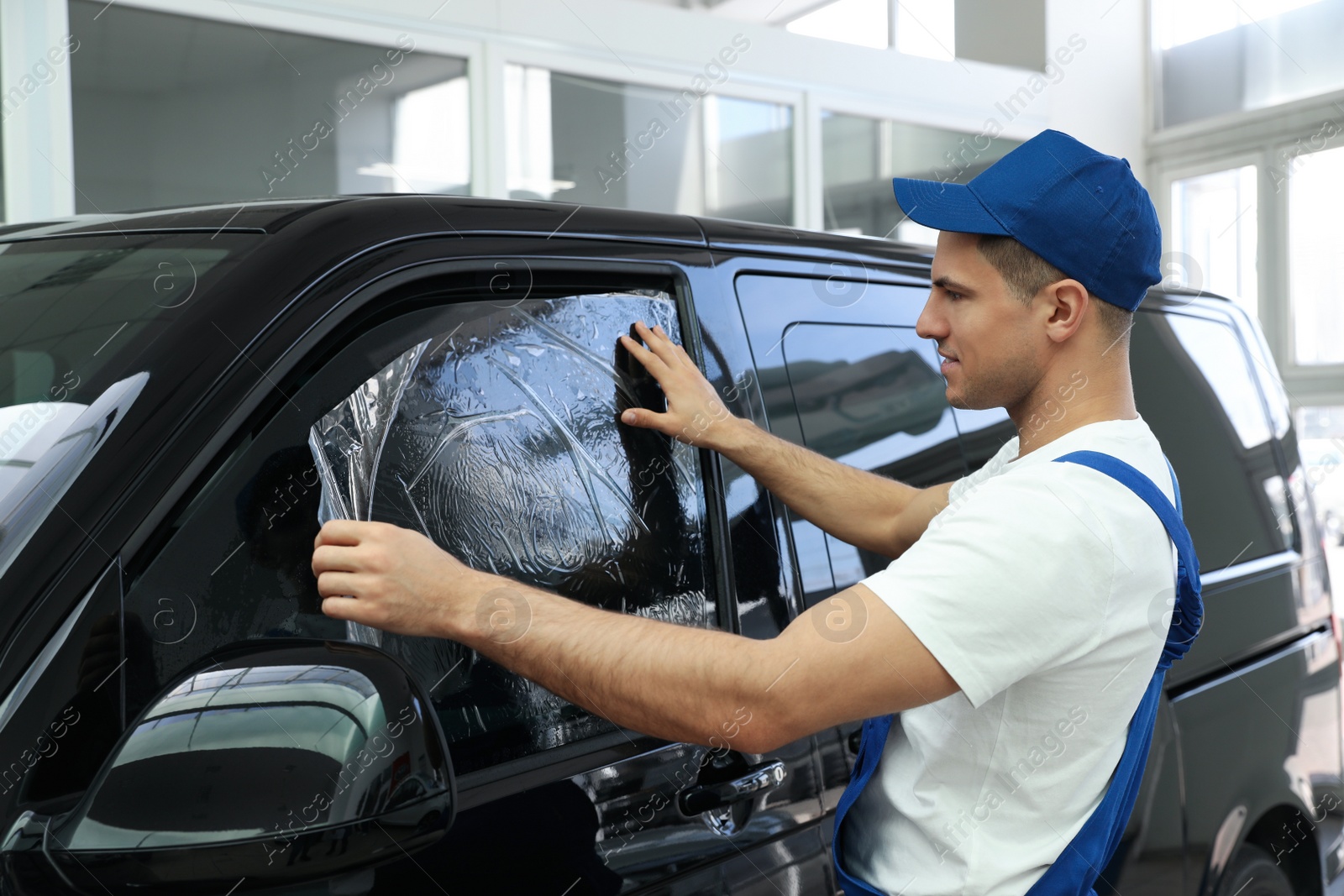 Photo of Worker tinting car window with foil in workshop